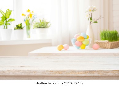 Easter table with colorful eggs and spring flowers on blurred kitchen window background