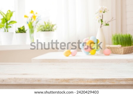 Easter table with colorful eggs and spring flowers on blurred kitchen window background
