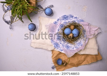 Easter table decor in blue colors with painted eggs in nests, top view