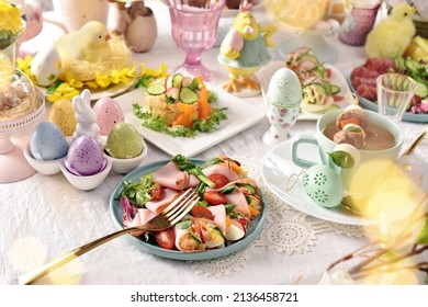 Easter table with ham cones filled with vegetable salad, eggs and white borscht with quail egg and sausage skewer