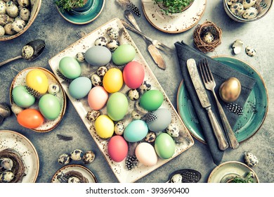 Easter table place setting decoration with colorful eggs. Vintage style toned photo