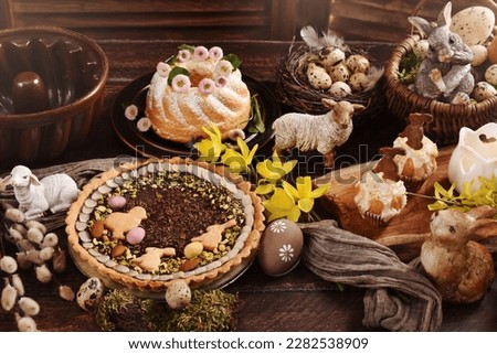 Easter table in rustic style with traditional pastries-Mazurek with chocolate and pistachios, ring cake and cup cakes with bunny shape cookies