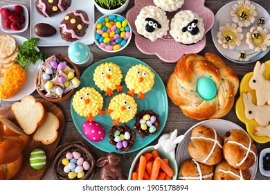 Easter table scene with an assortment of breads, desserts and treats. Top view over a wood background. Spring holiday food concept.