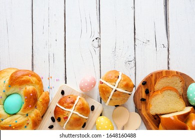 Easter table scene with an assortment of fresh breads. Overhead view bottom border over a white wood background. Spring holiday baking concept.