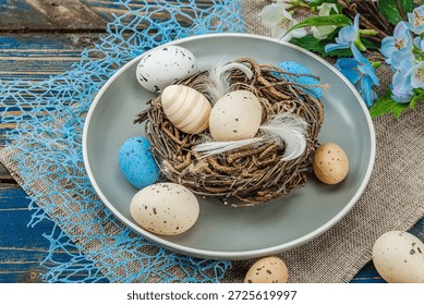 Easter table setting with eggs, bird's nest and blooming branch. Traditional festive symbols, greeting card, flat lay. Old wooden boards background, close up