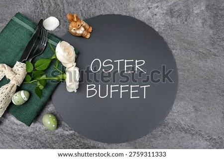 Easter table setting. Modern Easter buffet place setting on a slate platter with white roses and a dark green napkin. The German translation is  Easter buffett.
