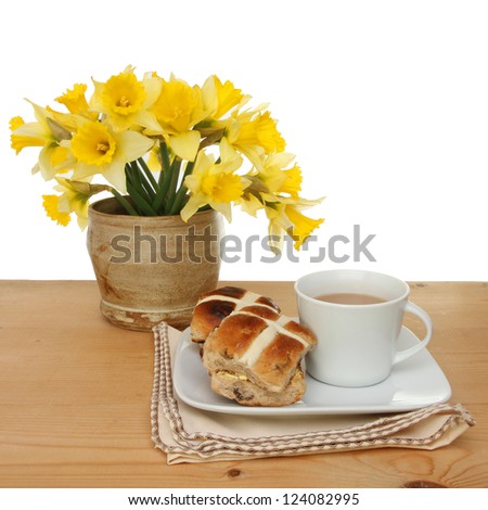 Easter theme, hot cross buns and a cup of tea with daffodil flowers on a table against a white background