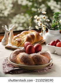 Easter traditional bread  austrian ostern zopf  greek tsoureki   red eggs table and linen tablecloth and spring window view  still life