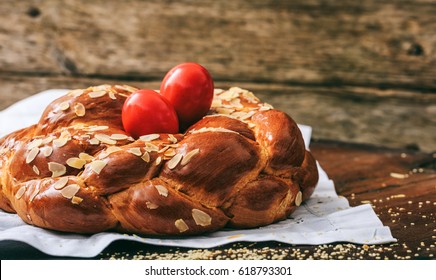 Easter traditional bread, greek tsoureki and red eggs on a wooden table, closeup view, copy space