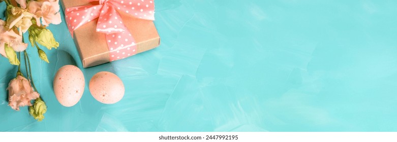 Easter turquoise banner with Easter decorations of trendy peach color. Decorative eggs, delicate Eustoma flowers, gift box with polka dots ribbon. Copy space for text. Top view. Invitation template. - Powered by Shutterstock