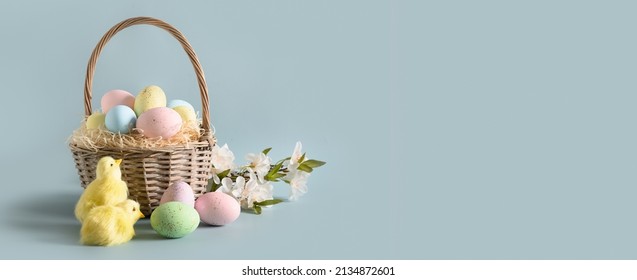 Easter wicker basket with pastel eggs for Happy holiday and celebration on blue background. Banner. Greeting card.