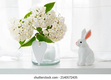 Easter wooden handmade bunny with a bouquet of white flowers and a white wooden heart