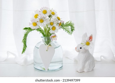 Easter wooden handmade rabbit with a bouquet of daisies and a white wooden heart