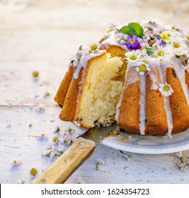 Easter yeast cake (Babka) covered with icing and decorated with edible flowers on a white plate on a white wooden table, close-up. Traditional Easter cake in Poland - Powered by Shutterstock