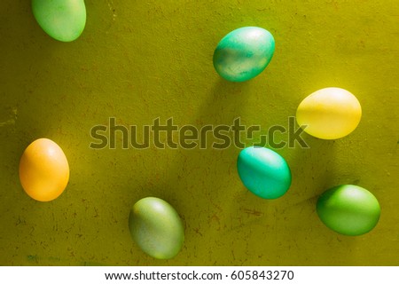 Easter yellow and green eggs are scattered on the old wooden background with free space for text