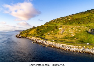 The Eastern Coast Of Northern Ireland And Antrim Coast Road, A.k.a. Giant's Causeway Coastal Route With Cars. Aerial View At Sunrise.