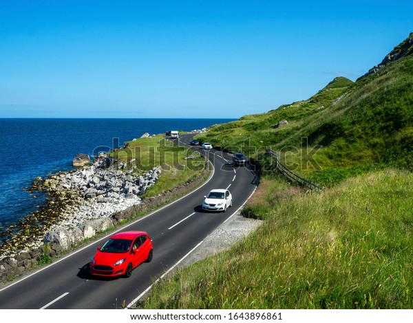 The eastern coast of Northern Ireland and\
Antrim Coast Road A2, a.k.a Causeway Coastal Route with cars. One\
of the most scenic coastal roads in\
Europe