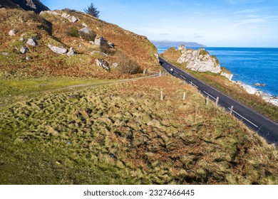 The eastern coast of Northern Ireland and Causeway Coastal Route with a cyclist. One of the most scenic coastal roads in Europe. Aerial view in winter - Powered by Shutterstock