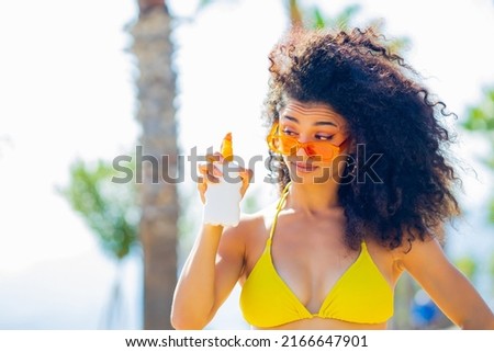eastern ethnic woman with long curls holding bottle cream from sun rays