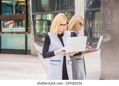 Eastern European Business Woman Working At High Tech Firm In New York, Wearing Long Vest, Black Undershirt, Glasses, Standing By Metal Mirror, Working On Laptop Computer. Color Filtered Effect
