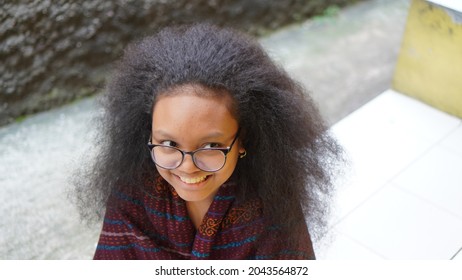 Eastern Indonesian (included In The Polynesian Family) With Curly Hair In Woven Sarong With Glasses Who Is Glancing And Smiling.