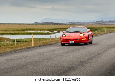Eastern Region, Iceland - June 18, 2016: Red Pontiac Firebird sport car drive on a road in countryside on gloomy summer day