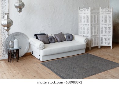 Eastern traditional interior. Morocco style room. Arch and window with beautiful carving. White and gray room with beautiful white sofa and pillows