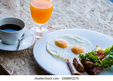 easy breakfast set with fried eggs, ham, sausage, coffee and orange juice. 