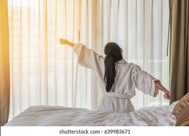 Easy lifestyle Asian woman waking up in the morning taking some rest relaxing in hotel room
