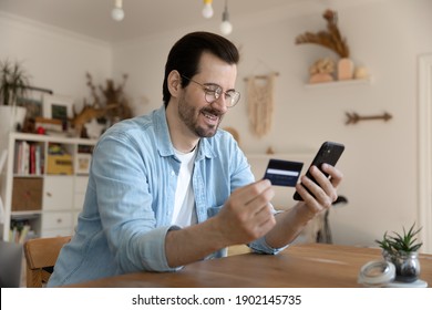 Easy paying. Happy millennial man use debit plastic card mobile telephone to provide loan mortgage payment online. Young male loyal bank client refill balance receive cash reward on electronic wallet