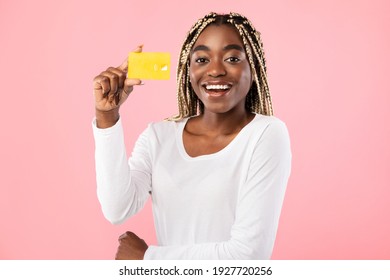 Easy Payment Concept. Portrait Of Smiling Casual Young African American Woman Holding Debit Credit Card In Hand And Showing It To Camera, Standing And Posing Isolated Over Pink Studio Background