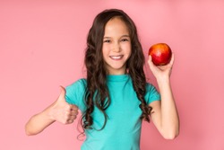 Eat Fruits. Girl Holding Apple And Showing Thumb Up Over Pink Background