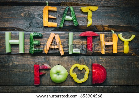 Eat healthy food fresh vegetables flat lay lettering on dark wooden table top view. Nutrition organic meal ingredients concept. Nice cooking postcard, poster, banner.