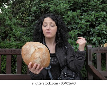 To Eat Or Not To Eat - Portrait Of Pretty Young Goth Brunette Woman Girl Female Model Looking At Huge Bread In Hamletic Pose As In Shakespeare Hamlet, London