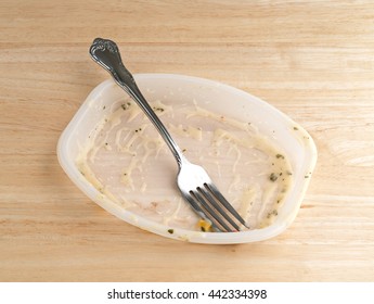 An Eaten TV Dinner On A Wood Table With A Fork In The Empty Plastic Tray.