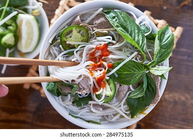 Eating Beef Pho With Spicy Sriracha Sauce Shot Top Down