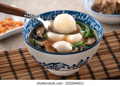 Eating big tangyuan yuanxiao (tang yuan, glutinous rice dumpling balls) with savory soup in a bowl for Winter solstice festival. - Shutterstock ID 2232044311