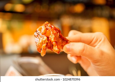 Eating Buffalo Chicken Wings With His Hands On A Blurred Restaurant Background.