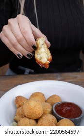 Eating Cheese Balls At The Restaurant. Closeup View Of A Caucasian Woman's Hand, Dipping A Potato And Mozzarella Croquette In Sweet Chili Dipping Sauce.