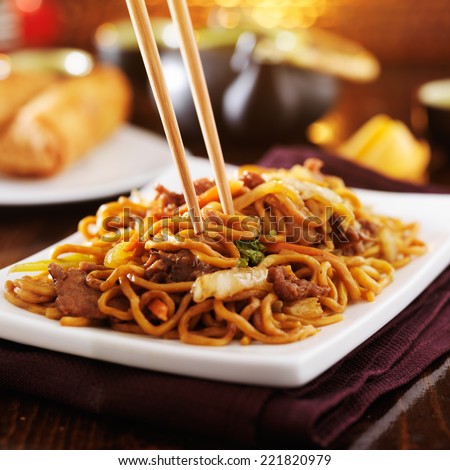 eating chinese beef lo mein with chopsticks