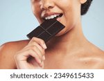 Eating, chocolate and woman in studio with unhealthy, diet or luxury snack on blue background. Sugar, bite and lady model with cocoa candy bar craving, addiction or sweet satisfaction while isolated