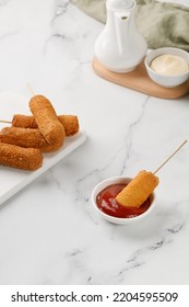 Eating Corn Dog With Ketchup, Red Sauce On White Marble Background. Traditional American Street Food. Fried Sausage On A Stick. Сorn Dog, Corndog.