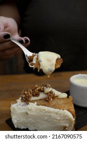 Eating Dessert. Closeup View Of A Woman's Hand Holding A Spoon With Carrot Cake With Passion Fruit Mousse. 