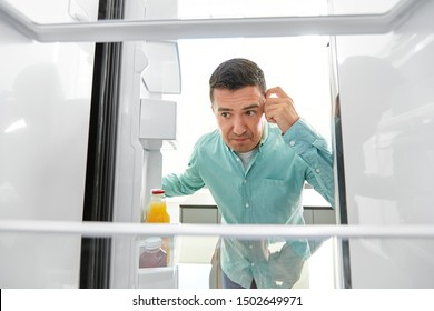 Eating And Diet Concept - Middle-aged Man Looking For Food In Empty Fridge At Kitchen