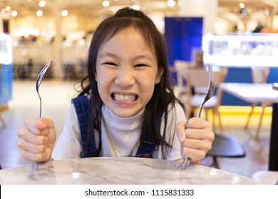 Eating disorder,Asian cute girl hungry waiting for lunch and order in the restaurant,Holding for a spoon and fork,hangry