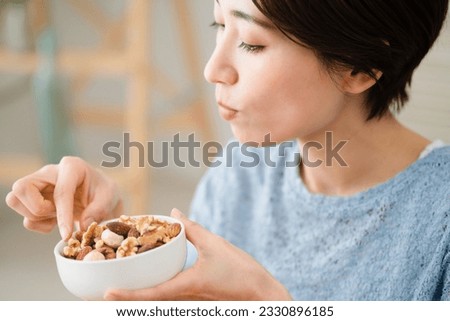 Eating and drinking image of a young woman eating mixed nuts
