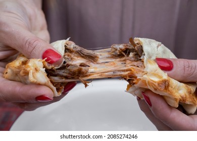 Eating empanadas. Closeup view of a woman hands breaking a flank steak meat and provolone cheese empanada. 