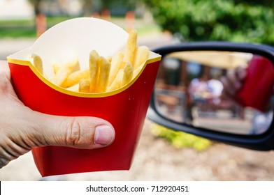 Eating Fast Food. Man Hands Holding McDonalds French Fries Outdoors Near The Car Mirror