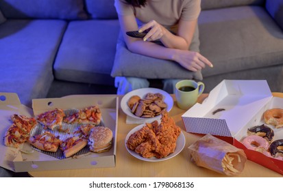 Eating Fast Food When Takeout And Delivery At Night. Takeaway Back Home And Watching TV. Asian Woman Lifestyle In Living Room. Social Distancing And New Normal.