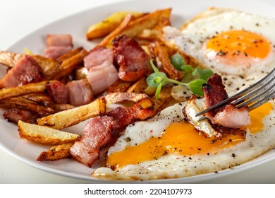 Eating French Fries With Fried Eggs And Bacon - Close Up View